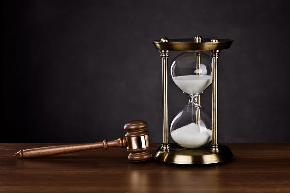 A mallet and hourglass resting on a desk to showcase the legal benefits and differences between compliance and conformity.